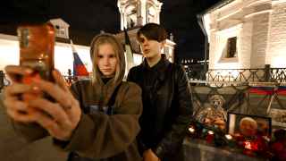 Пара фотографируется на фоне импровизированного мемориала в честь Евгения Пригожина и Дмитрия Уткина в Москве